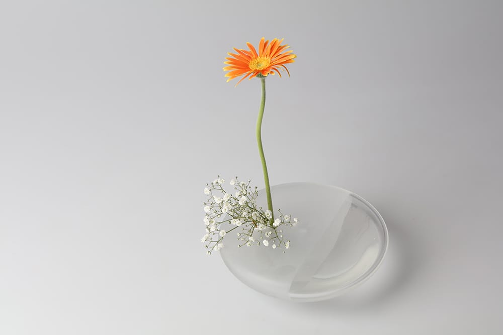 Flower vase “Sound of Waves ‐Clear‐” by Miya Kitamura. Kitamura created this piece imagining that “I listen carefully in a field with flowers and hear the sound of water flowing.”  Photography by Miya Kitamura