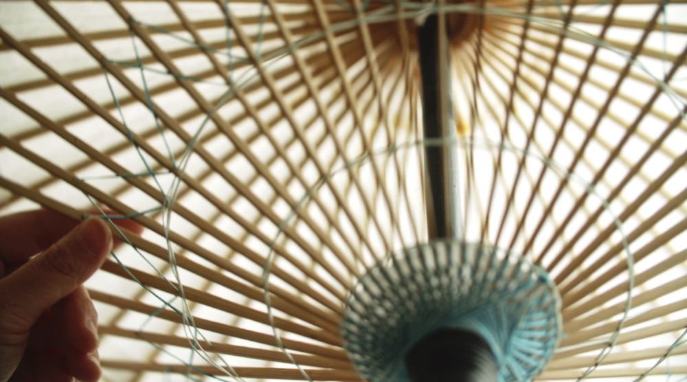 京都で唯一の和傘製造元、日吉屋による傘の制作の様子。竹の骨を手作業で組み、和紙を張り、油を紙に塗るといった工程を経て完成する。