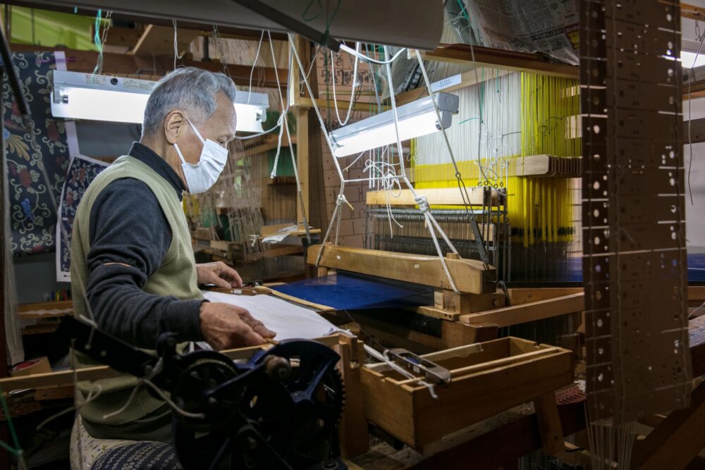 「鷹山」の水引を、昔ながらの手機（てばた）で織る「龍村美術織物」職人。
