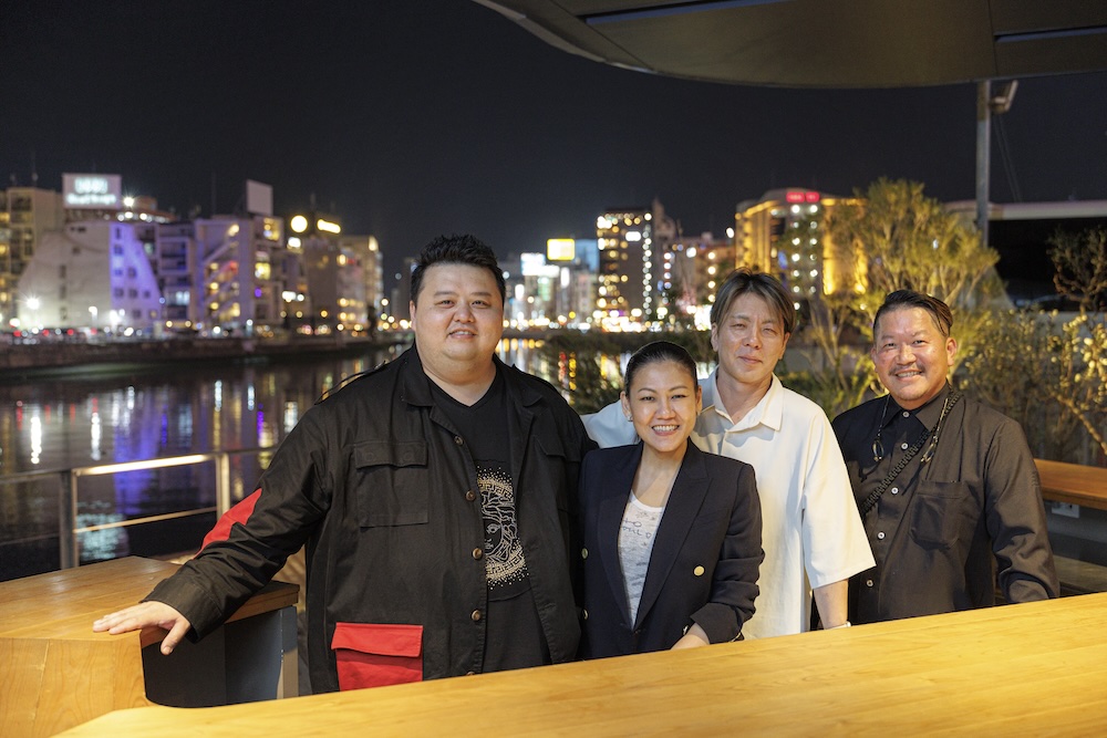 食後、中洲の夜景を背景に記念撮影。左からジェイソン・タンシェフ、ジョアン・シイシェフ、小林寛司シェフ、福山剛シェフ。