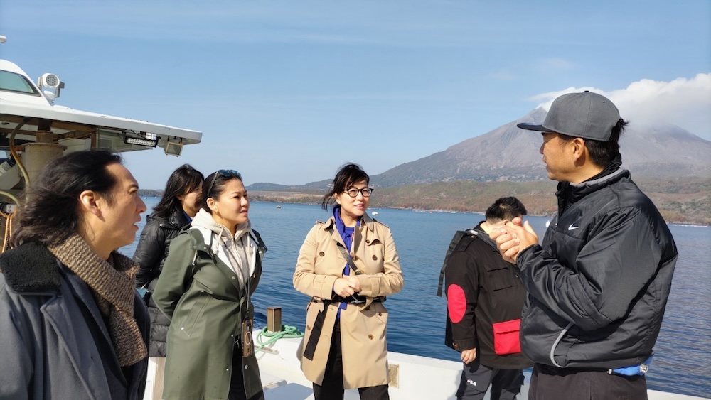 噴煙を上げる桜島を眺めつつ、実際に漁船に乗り込んで漁業者から鹿児島の魚介類についての説明を受ける。