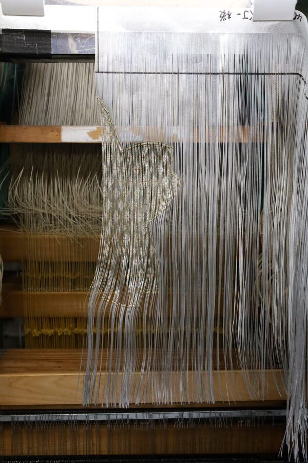 貝殻糸を機にかけ、織る工程。